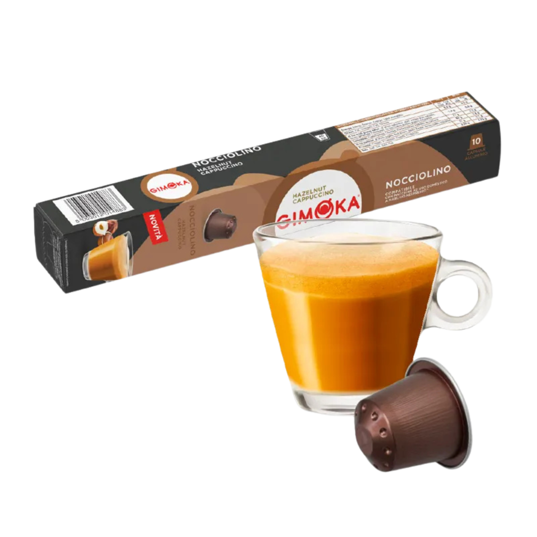Outin капсула за кафе и чаша с пенлива напитка, разположени на фона на кутия Gimoka Pistacchino.